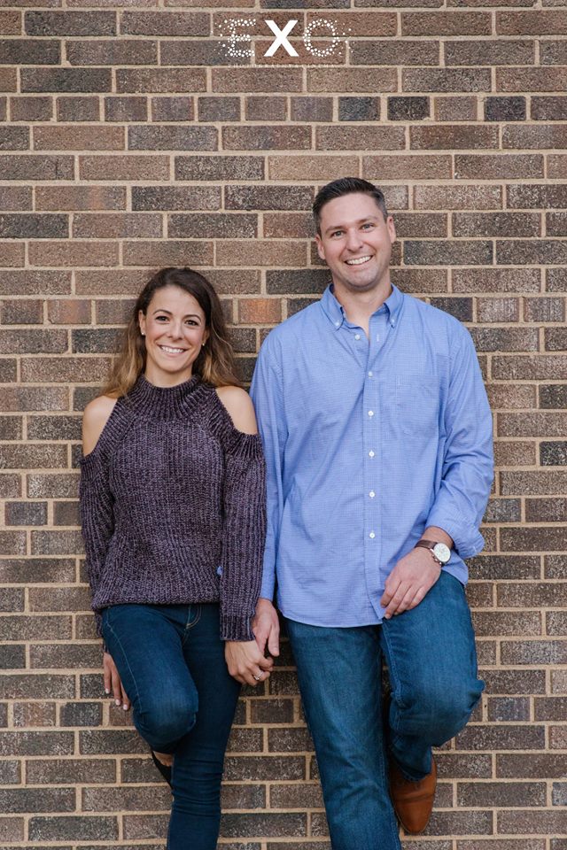 Couple posing in front of a brick wall