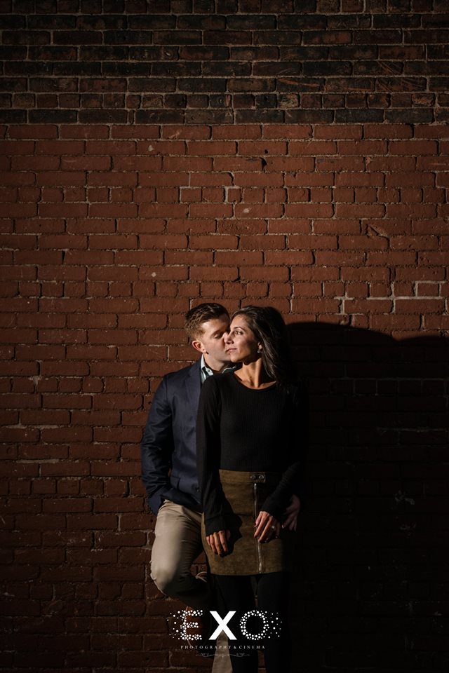 Couple in front of brick wall at DUMBO