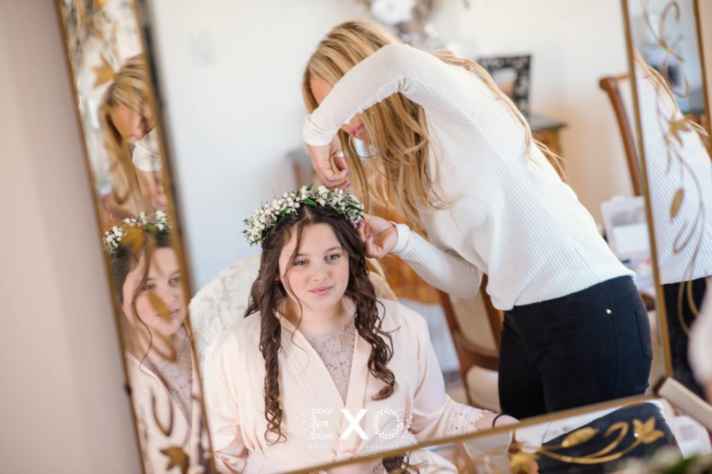 Flower girl getting hair done looking in mirror at The Mansion at Oyster Bay