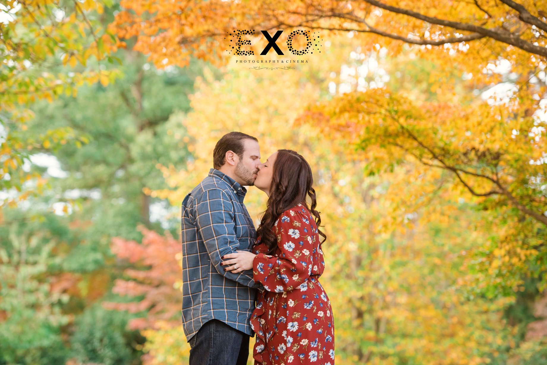 Couple kissing surrounded by fall trees