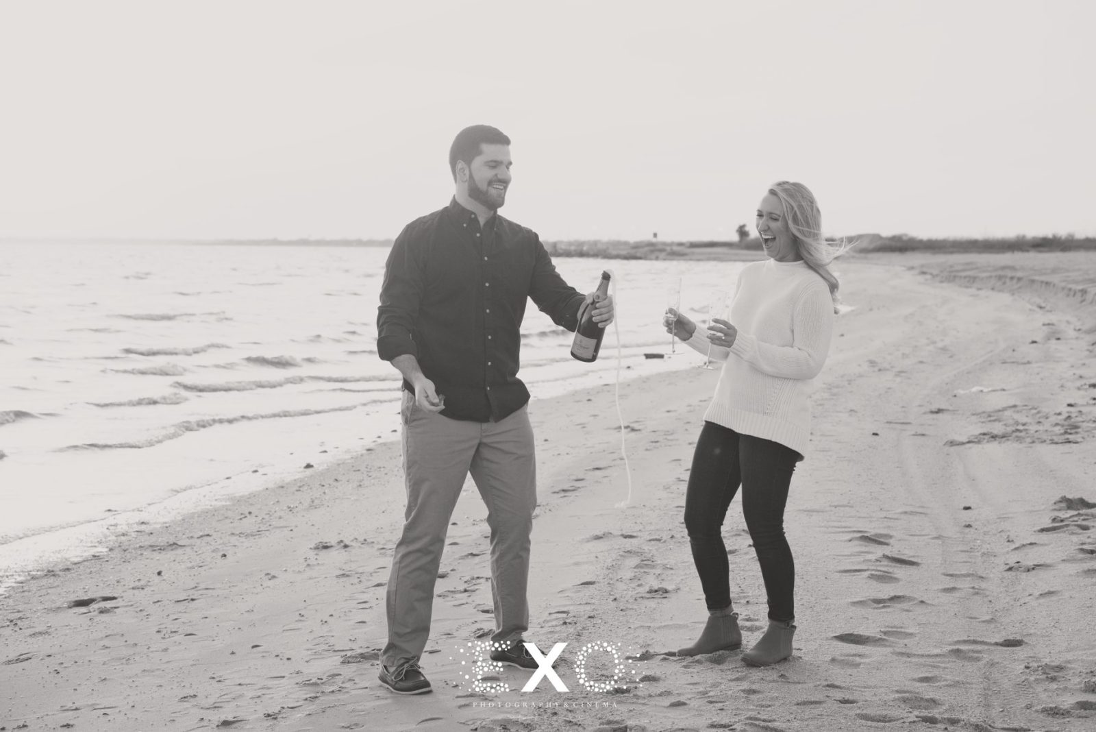 Couple popping champagne on the beach 