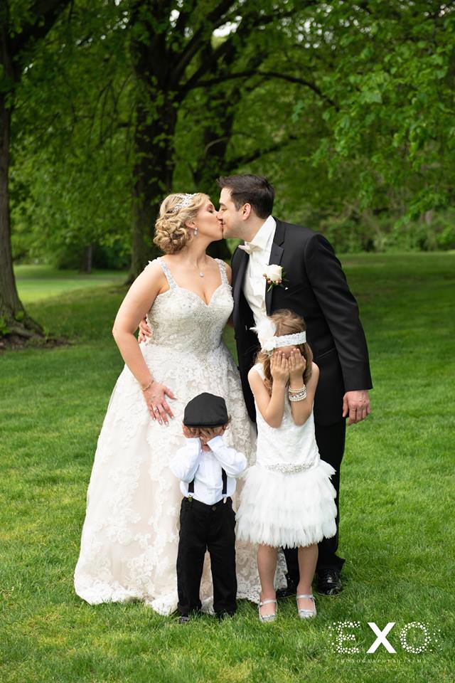 Bride and groom kissing with flower girl and ring bearer at The Mansion at Oyster Bay