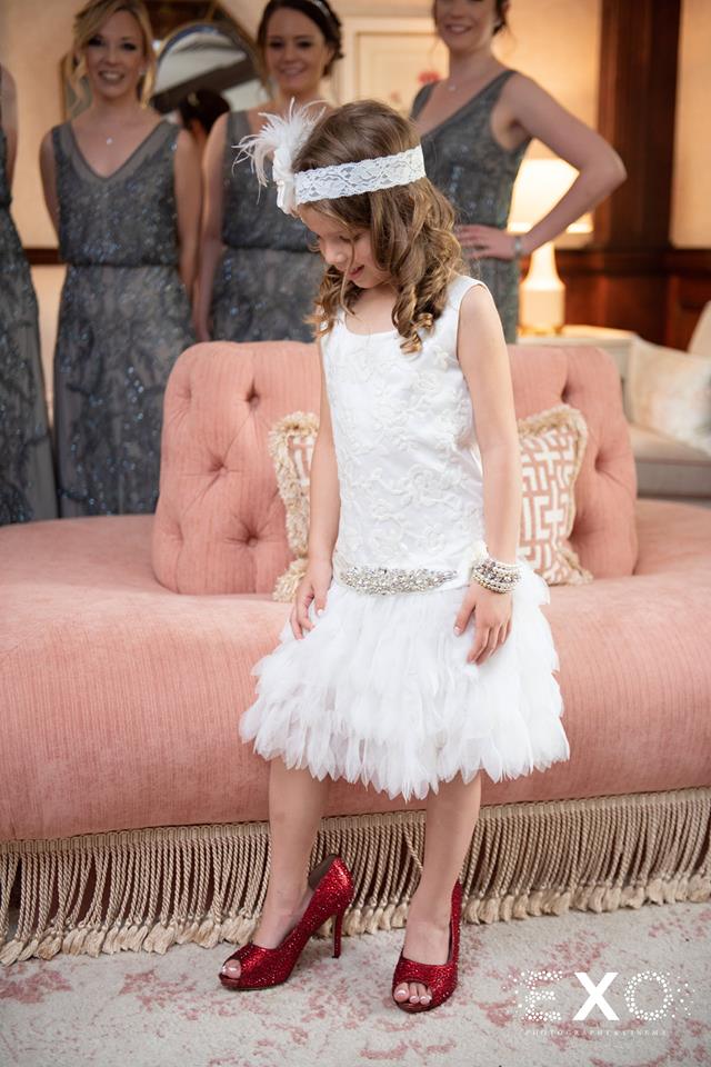 flower girl trying on bride's shoes at The Mansion at Oyster Bay