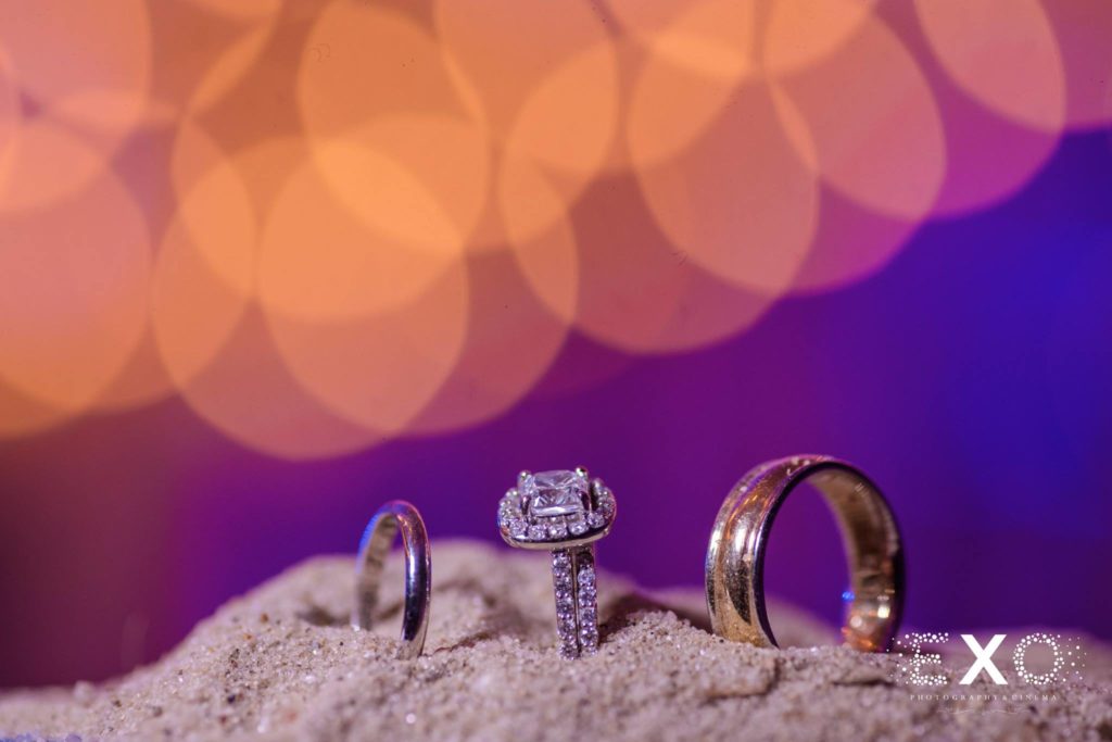 wedding bands and engagement ring in the sand