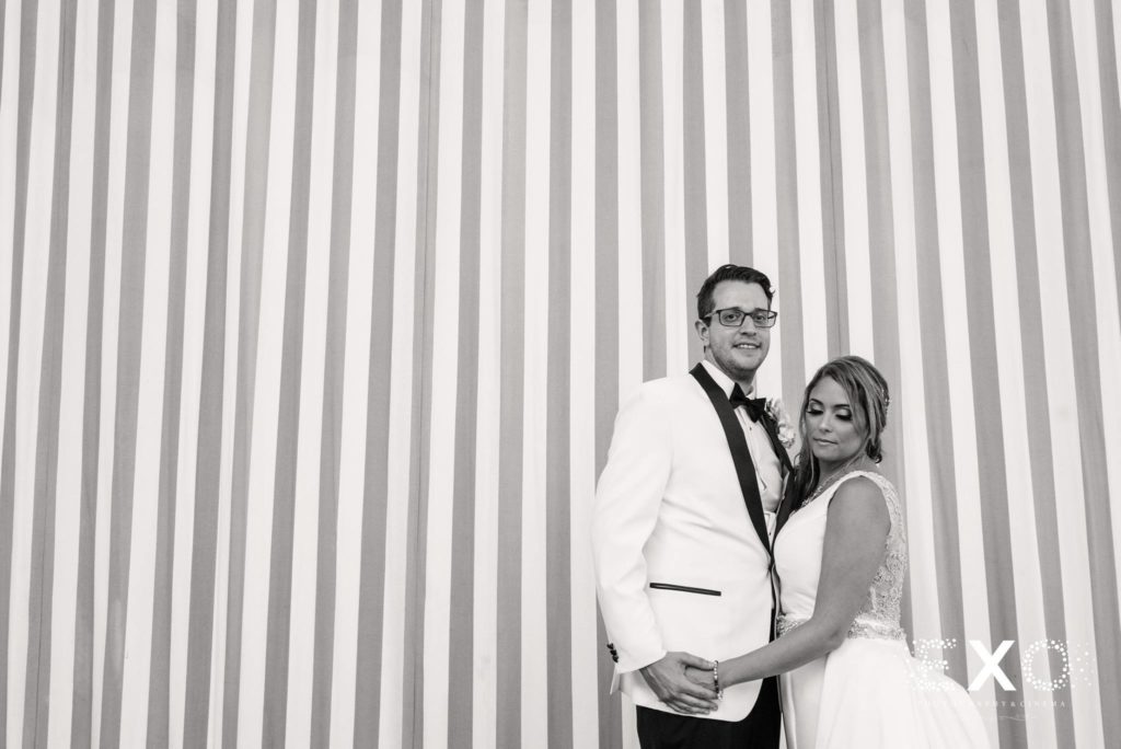 bride and groom against striped wall at Oceanbleu