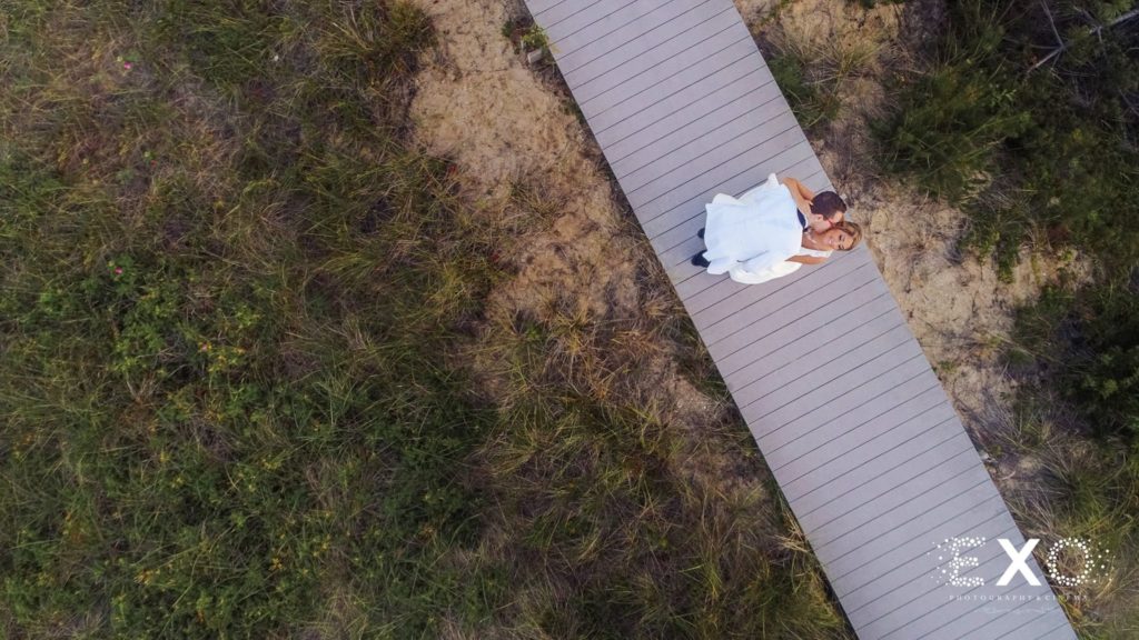 bride and groom on boardwalk, drone view