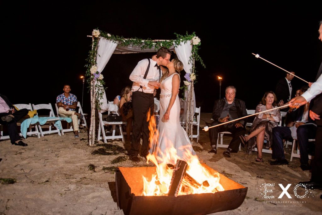 bride and groom kissing by the fire at Oceanbleu
