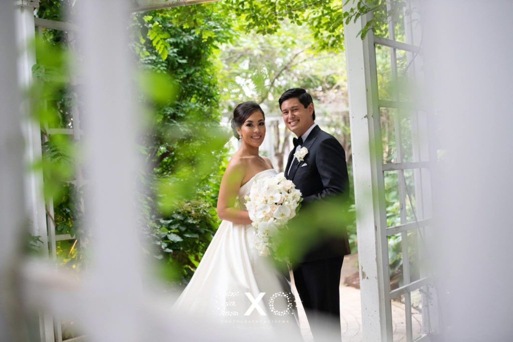 Bride and groom outside in the greenery at The Garden City Hotel