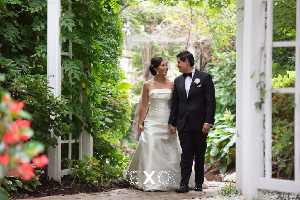 Bride and groom walking through the garden at The Garden City Hotel