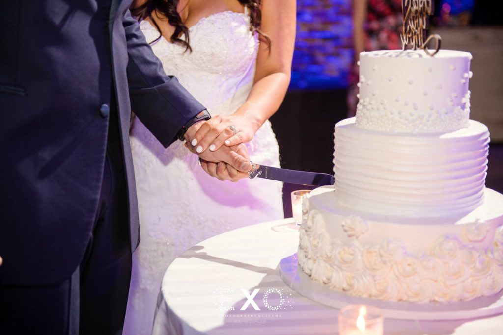 Bride and groom cutting into their white wedding cake at The Loft at Bridgeview Yacht Club