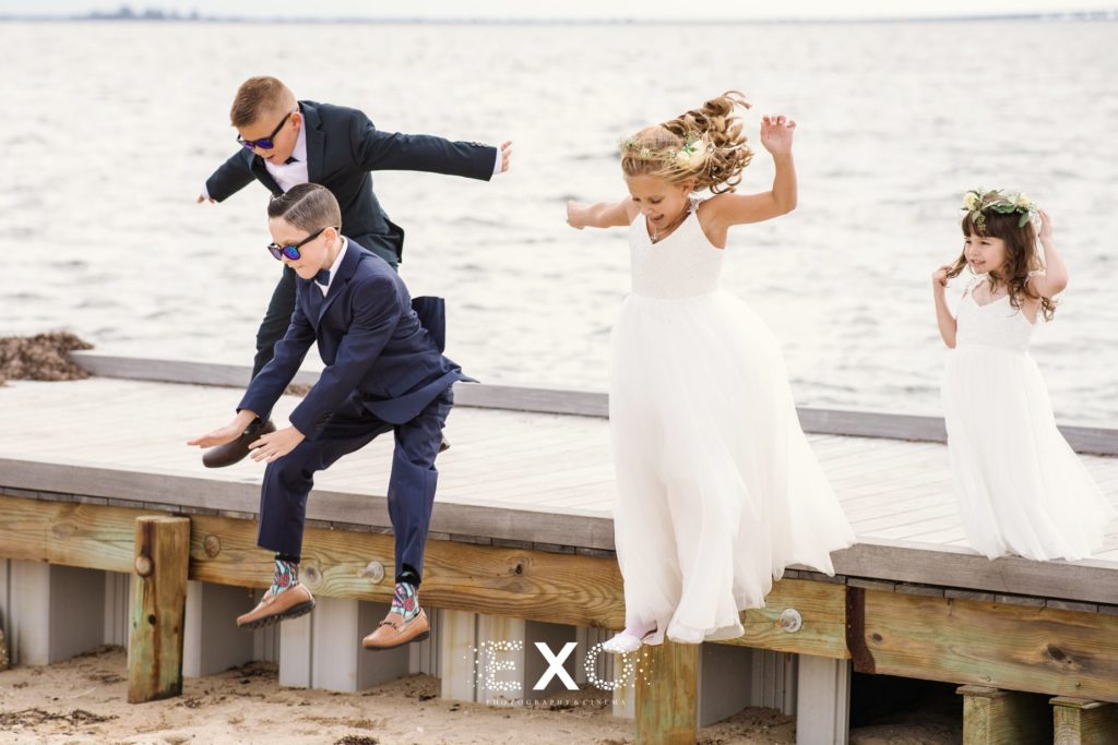 flower girls and ring bearers jumping off the dock into the sand at Captain Bills