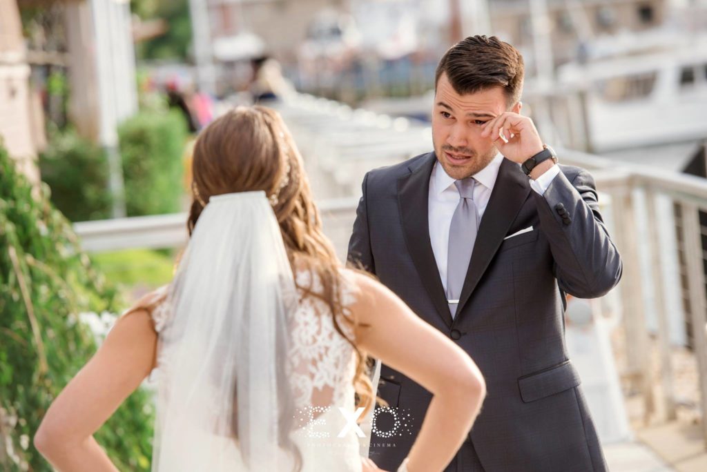 groom wiping tears during the first look at Harbor Club at Prime
