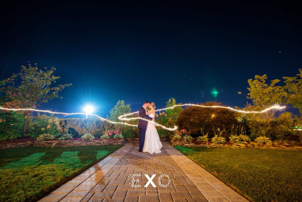 bride and groom in each other's arms with lights surrounding them at The Cottage at Milleridge