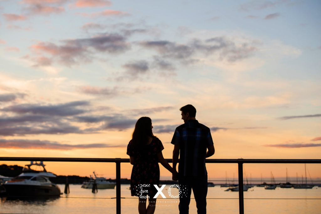 couple looking over the water with a sunset at Port Jefferson Harbor