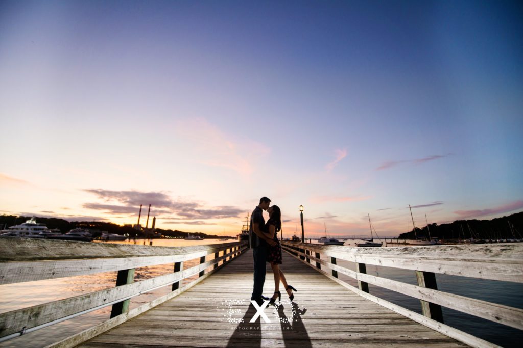 couple standing on dock with gorgeous sunset at Port Jefferson Harbor