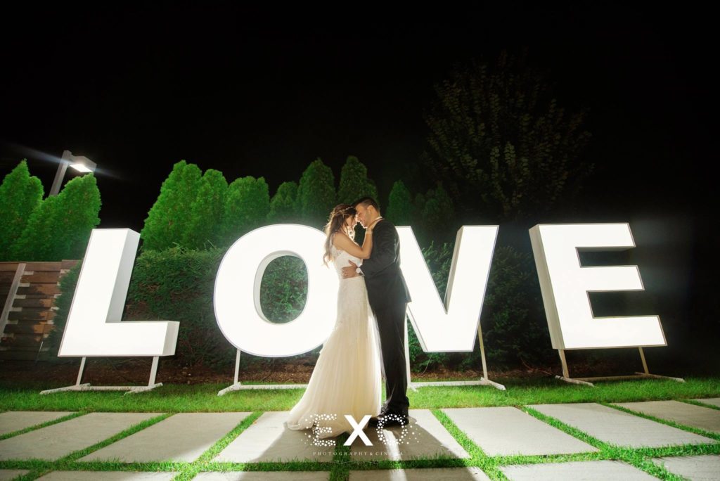 bride and groom in front of love sign at Harbor Club at Prime