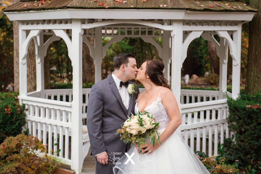 Bride and groom kissing outside gazebo at Fox Hollow