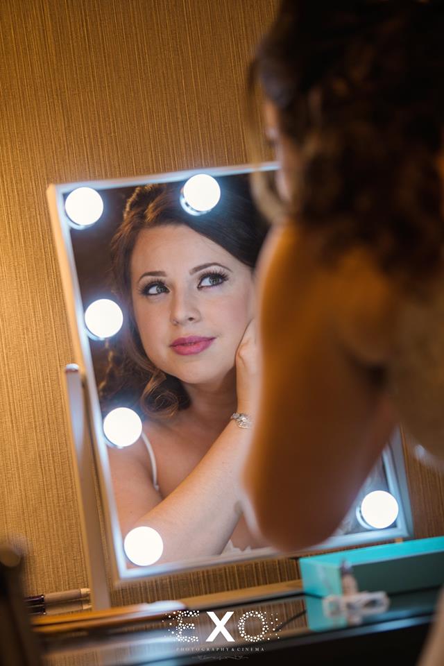 Bride putting in earrings looking in mirror