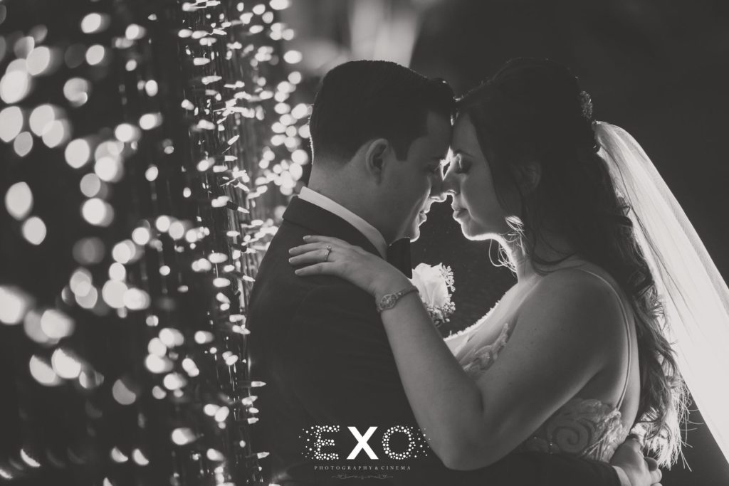 Bride and groom in black and white with string lights at Fox Hollow