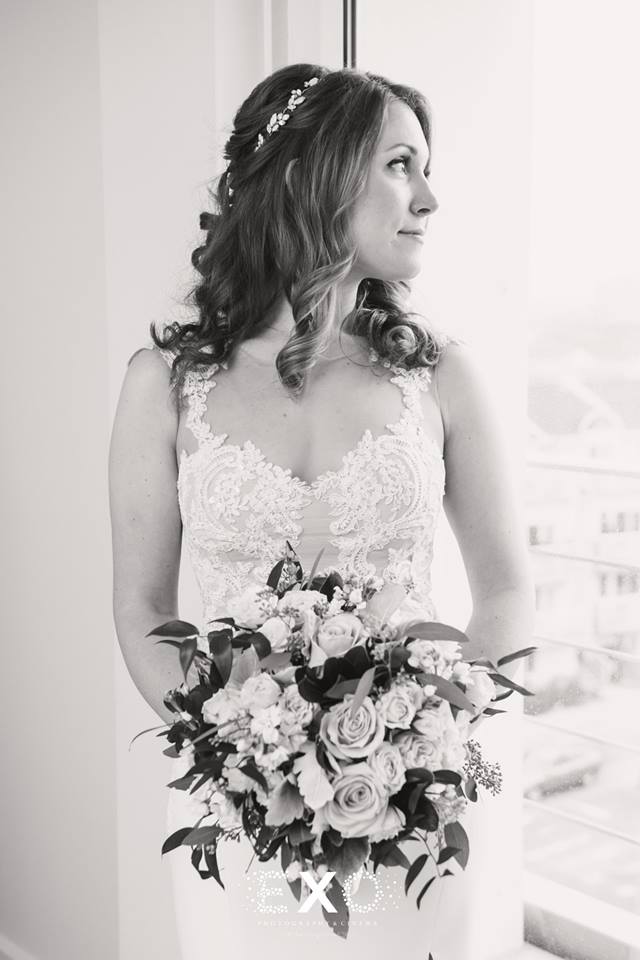 stunning bride with bouquet looking out the window at Allegria Hotel