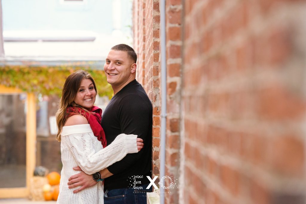 Couple smiling against brick wall