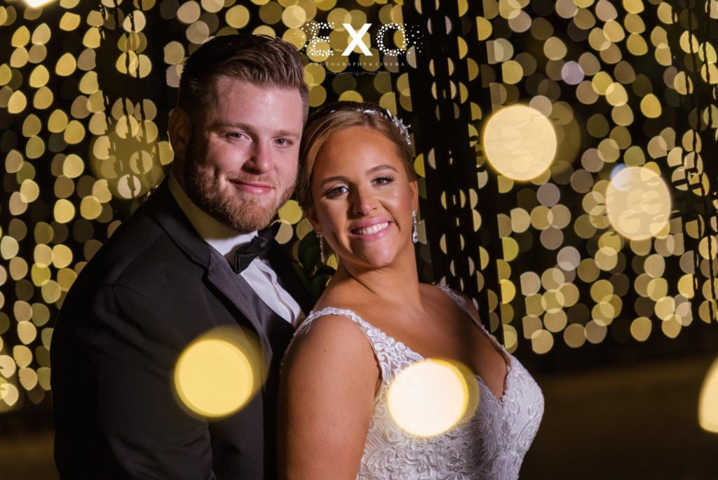 Bride and groom smiling in string lights