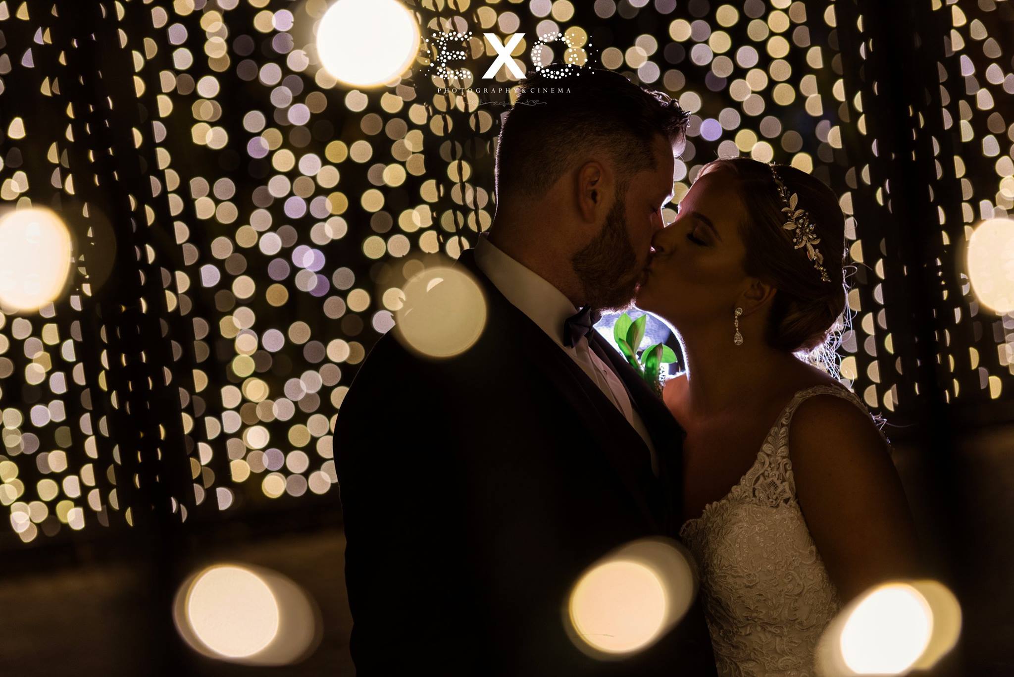 Bride and groom kissing in string lighting at Fox Hollow