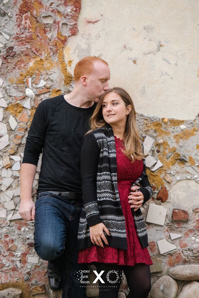 Couple leaning against rustic wall at Heckscher Park