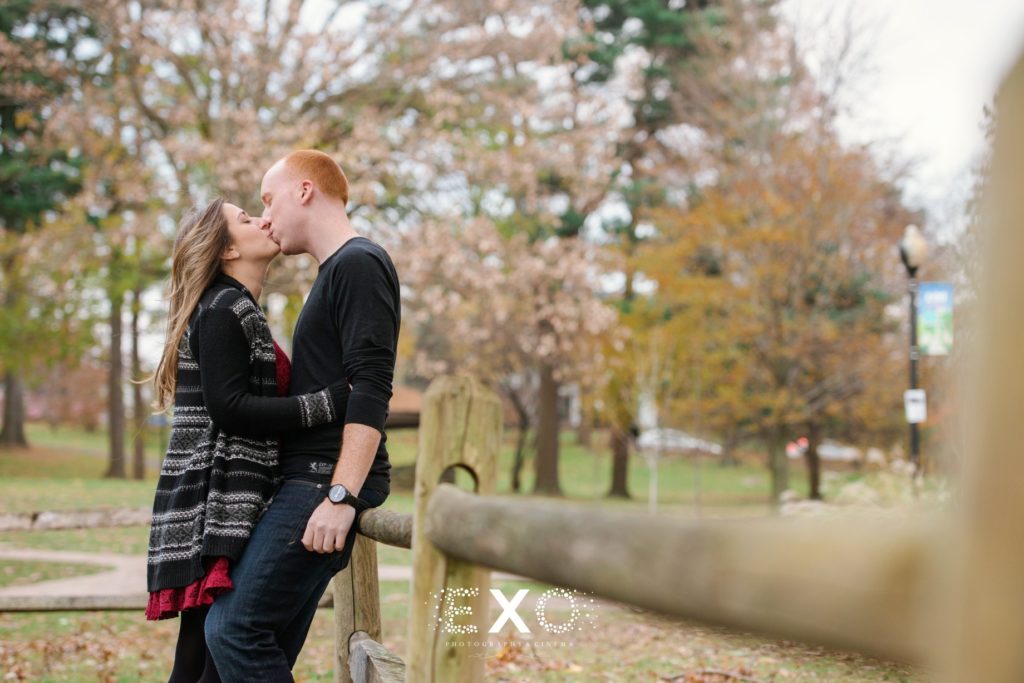 Couple kissing against fence at Heckscher Park