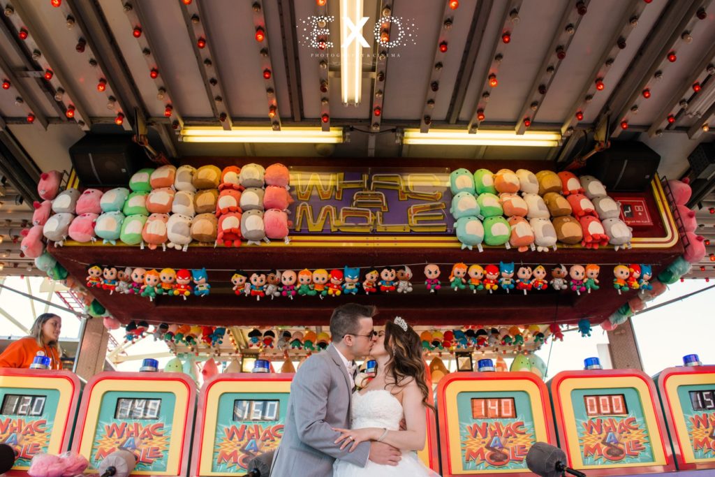 Bride and groom kissing in front of wack-a-mole