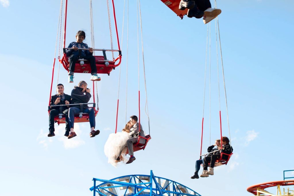 bride and groom on swings at amusement park