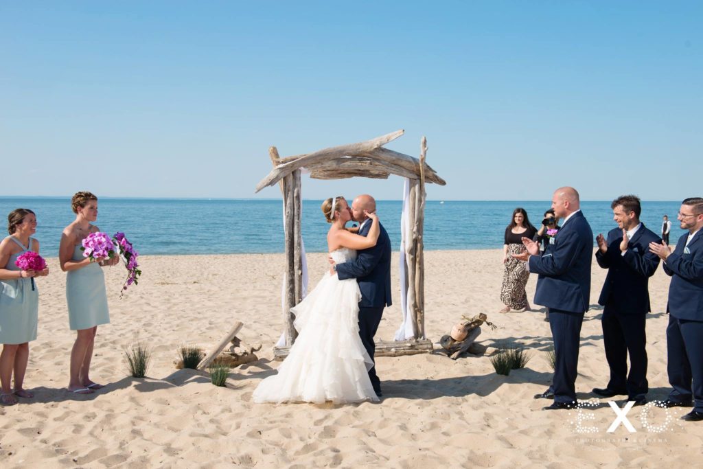 bride and groom kissing under ceremonial arch at Pavilion at Sunken Meadow
