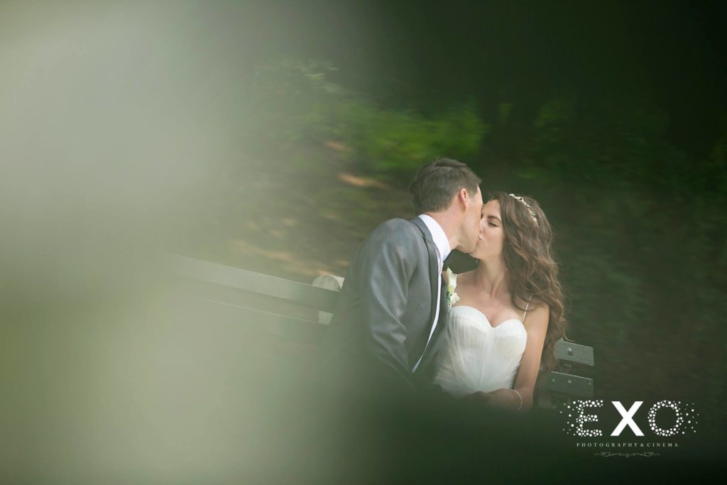bride and groom kissing on bench outside Villa Russo
