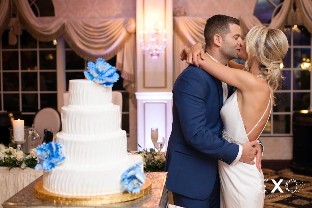bride and groom kissing next to their cake at Giorgio