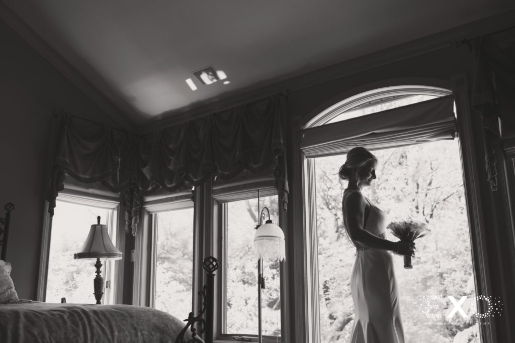 bride in window looking at her bouquet