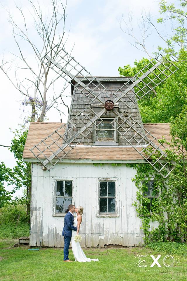 bride and groom kissing in front of an old windmill at Giorgio