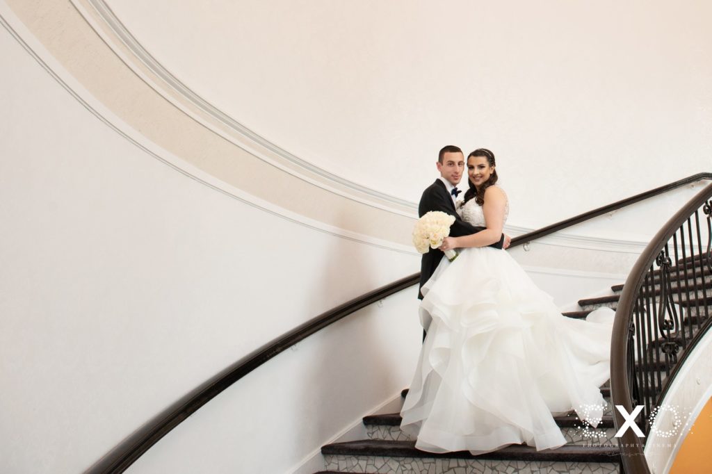 bride and groom smiling on stairs at Temple Beth El Cedarhurst