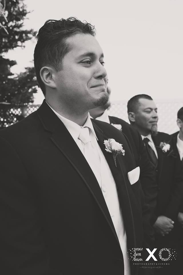 groom crying while his bride walks down the aisle