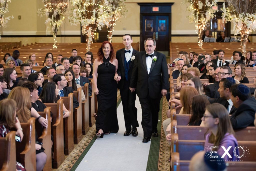 groom walking down the aisle with his family