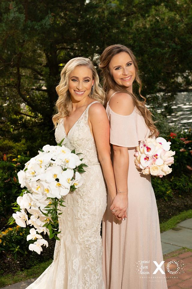 bride and sister with bouquets holding hands