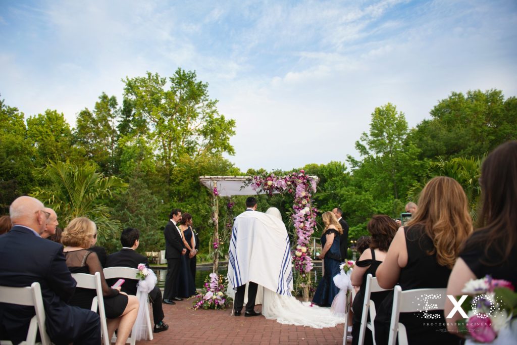 bride and groom standing under chuppah