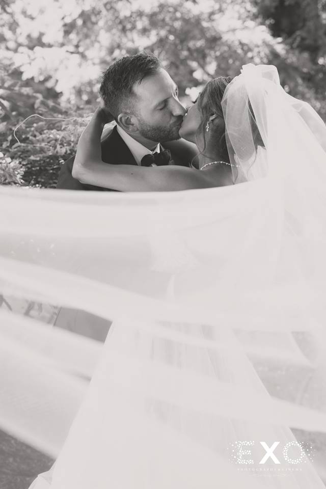 bride and groom kissing with bride's veil blowing