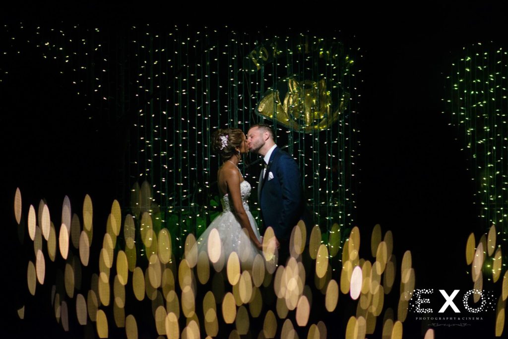 bride and groom kissing in string lights