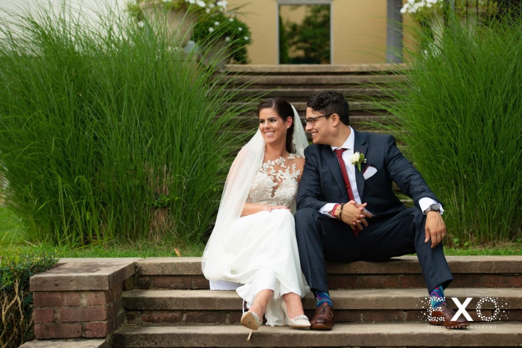 bride and groom sitting on the steps outside The Mansion at Oyster Bay