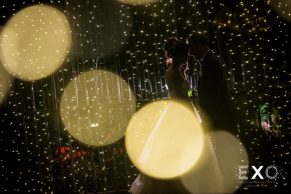 bride and groom in string lights at Fox Hollow