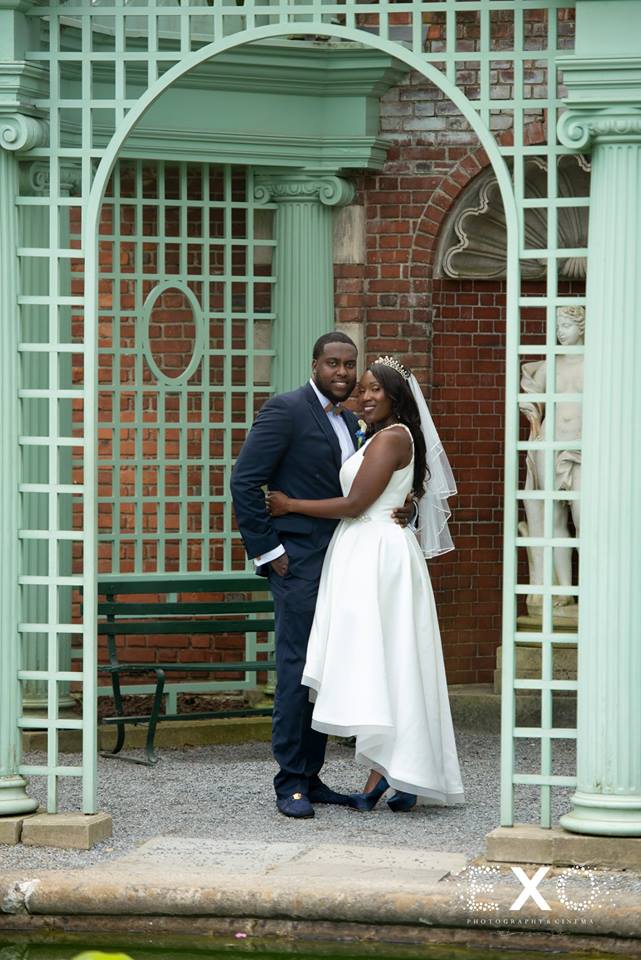 bride and groom posing in archway at Old Westbury Gardens