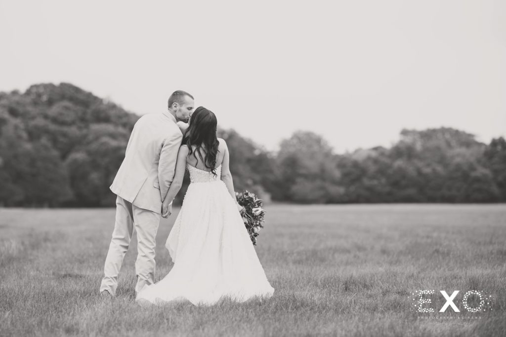 bride and groom kissing in field at Bourne Mansion
