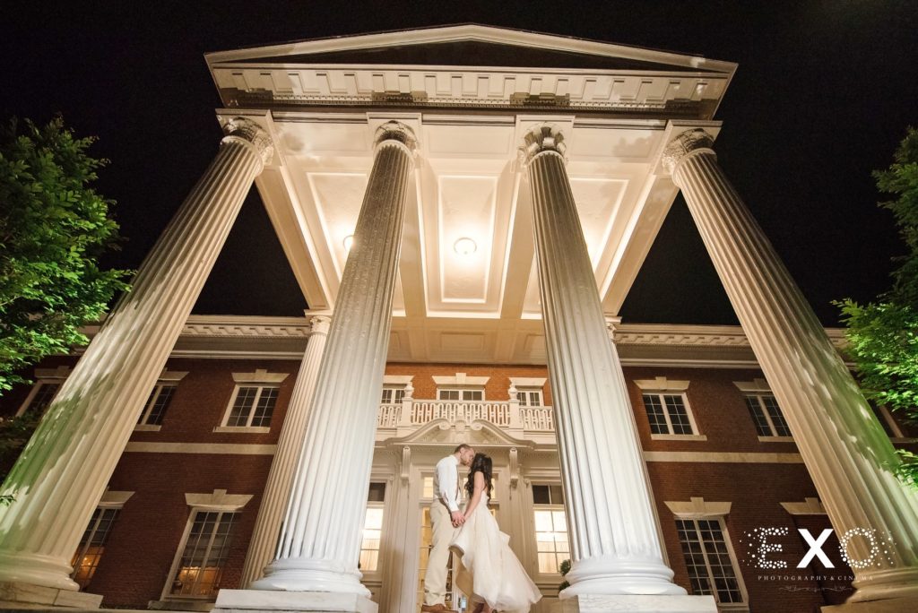 bride and groom kissing in front of Bourne Mansion
