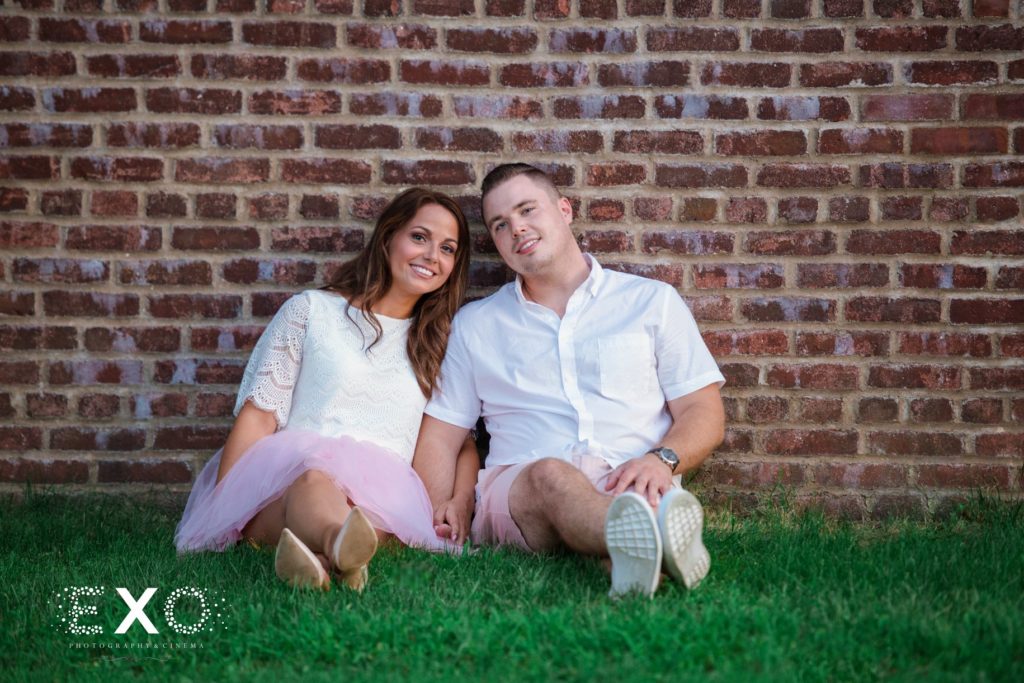 couple sitting against brick wall