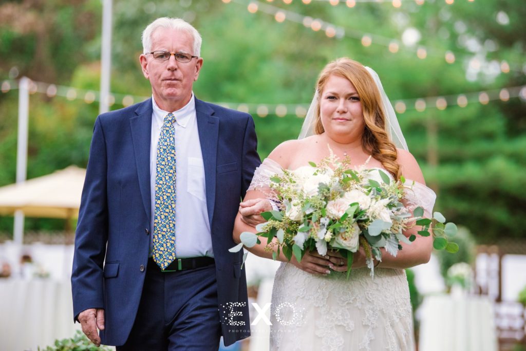 bride's father walking her down the aisle at their private residence